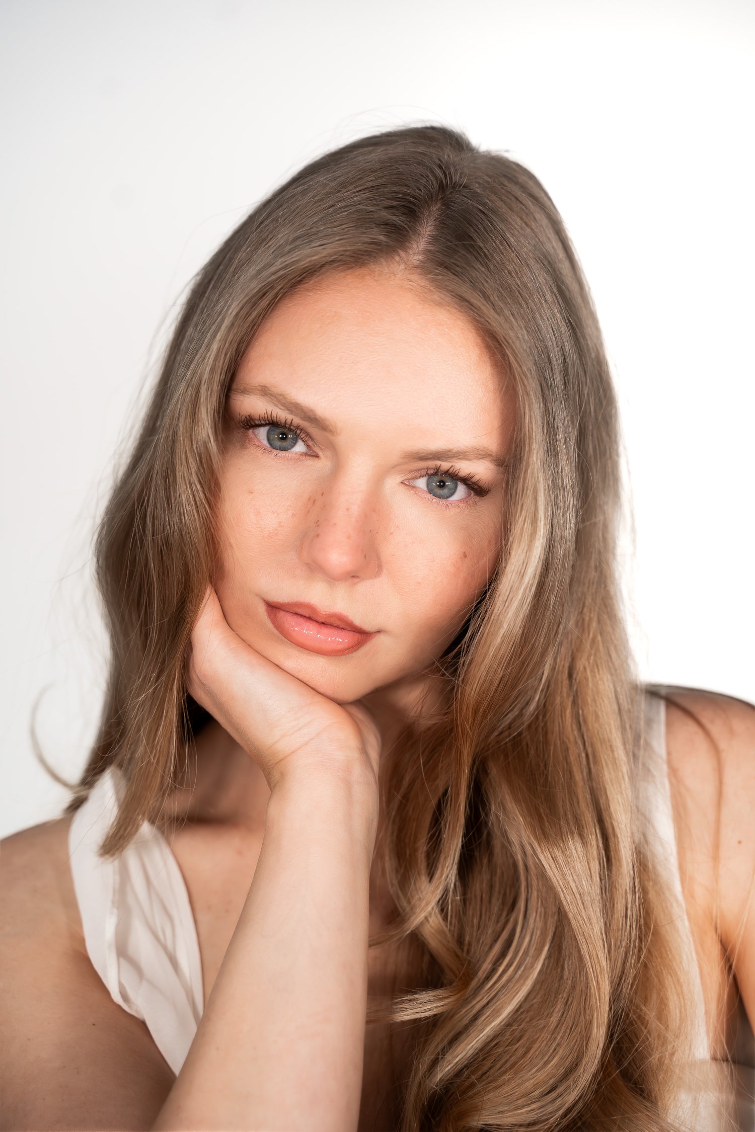 Woman with long blonde hair posing against a white background